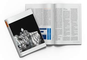A magazine with a silver chess king and pieces on its cover, lying beside an open magazine spread with text and charts.
